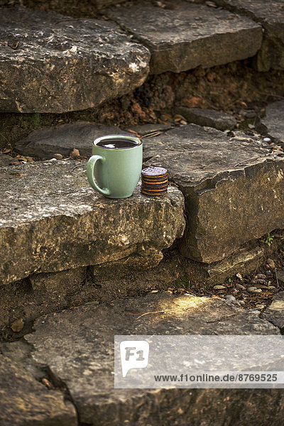 Tasse schwarzer Kaffee und Schokokekse auf Steintreppe