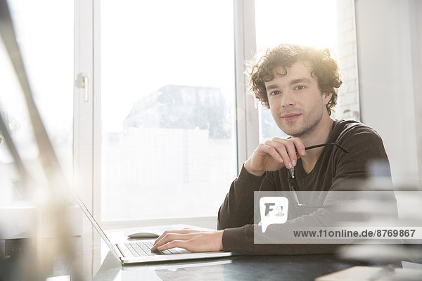 Portrait of young architect sitting at desktop in his office