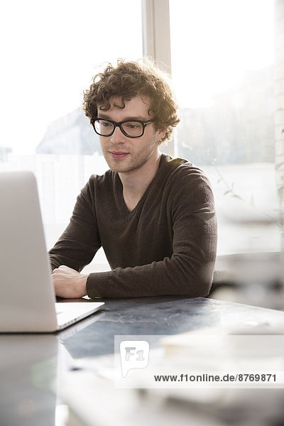 Portrait eines jungen Architekten mit Laptop in seinem Büro