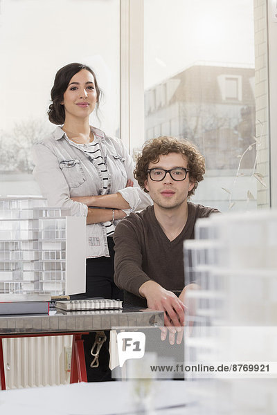 Portrait of two young architects with architectural model in office