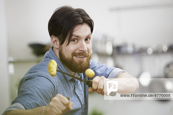 Mann beim Kartoffelspießen in der Küche