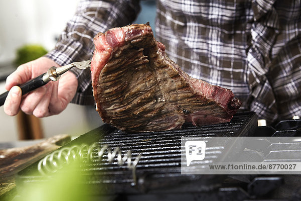 Close-up of woman grilling steak in kitchen