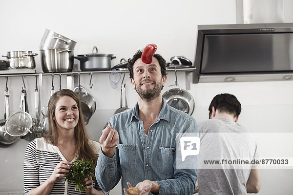 Mann jongliert mit Essen in der Küche