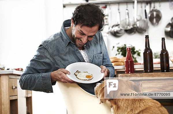 Man showing plate with fried egg to dog