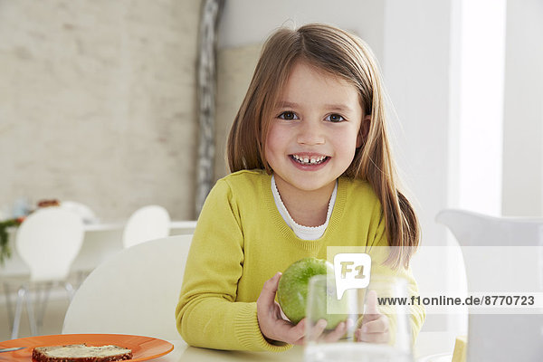 Girl sitting at table with green apple
