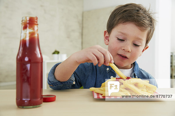 Junge isst Pommes frites mit Ketchup