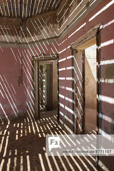 Light passing through the laths of a decaying house in the former diamond miners settlement that is slowly covered by the sand of the Namib Desert  Kolmanskop  ?Karas  Namibia