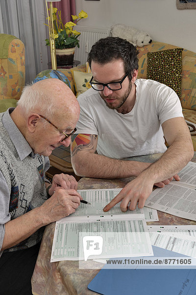 Enkel hilft seinem Großvater bei der Steuererklärung