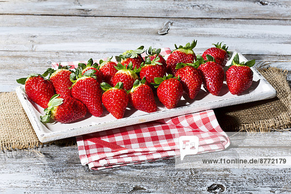 Platter of strawberries (Fragaria) on jute  kitchen towel and wooden table
