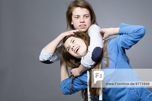 Teenagermädchen mit ihrer Schwester im Schwitzkasten