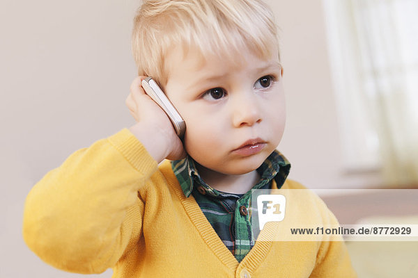 Porträt eines ernsthaft aussehenden Kleinkindes beim Telefonieren mit dem Smartphone