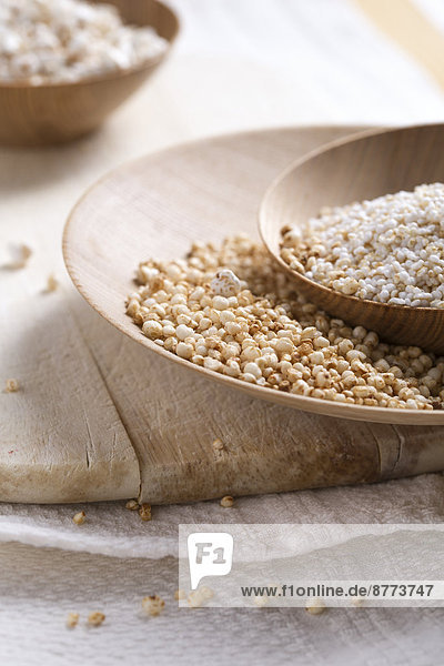 Bowls of puffed buckwheat  quinoa and amaranth on wooden board and kitchen towel