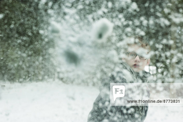 Boy throwing snowball against windscreen