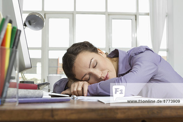 Woman at home sleeping at desk with computer