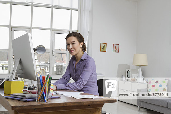 Woman at home sitting at desk with computer