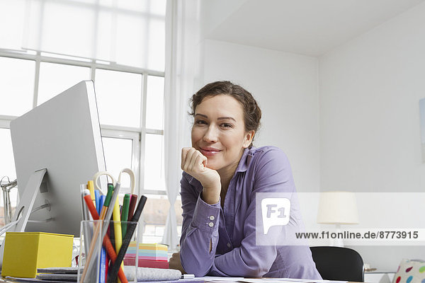 Frau zu Hause sitzend am Schreibtisch mit Computer