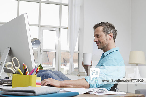 Man at home sitting at desk with computer