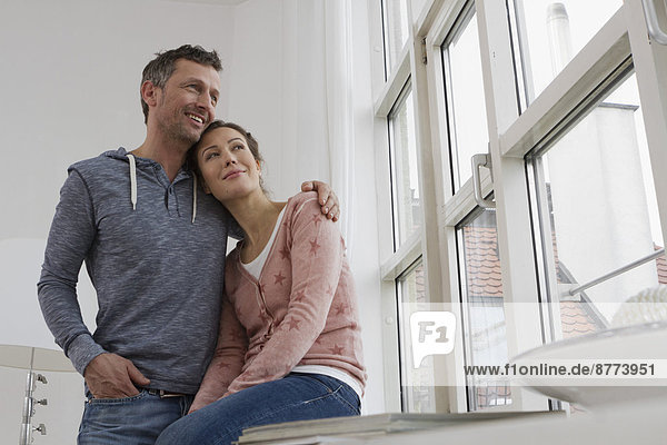 Smiling couple embracing at the window