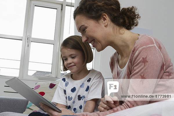 Mother and daughter on couch with tablet computer
