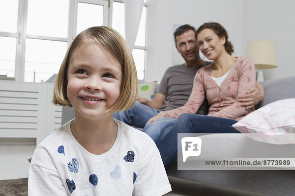 Blond girl in living room with parents in background