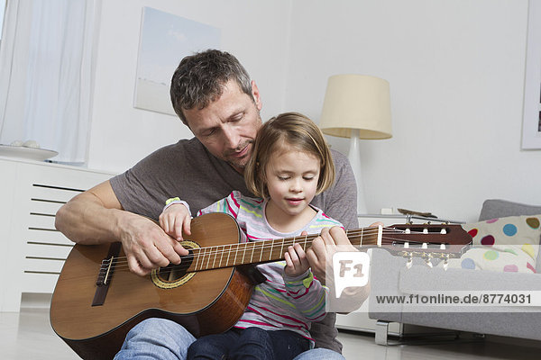 Vater lehrt Tochter Gitarre spielen