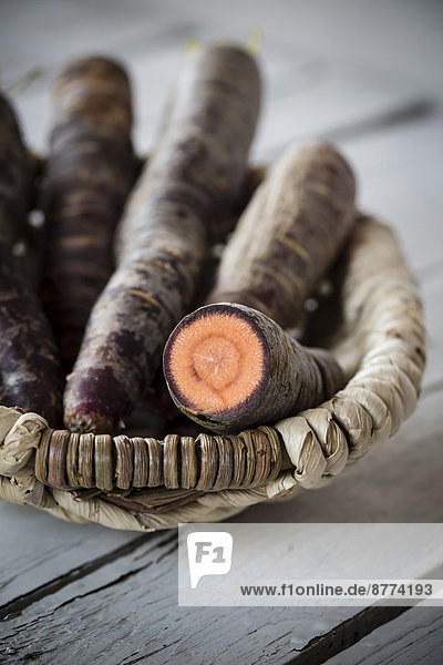 Korb mit Purple Haze Karotten auf grauem Holztisch  Nahaufnahme