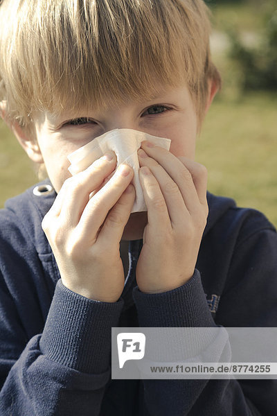 Portrait of boy blowing his nose with tissue handkerchief