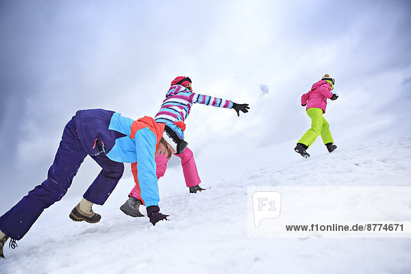 Two teenage girls and her mother having a snowball fight