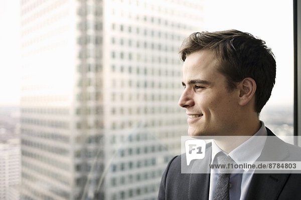 Porträt eines jungen Geschäftsmannes mit Blick aus dem Bürofenster