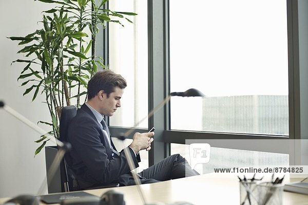 Young businessman texting on smartphone from office