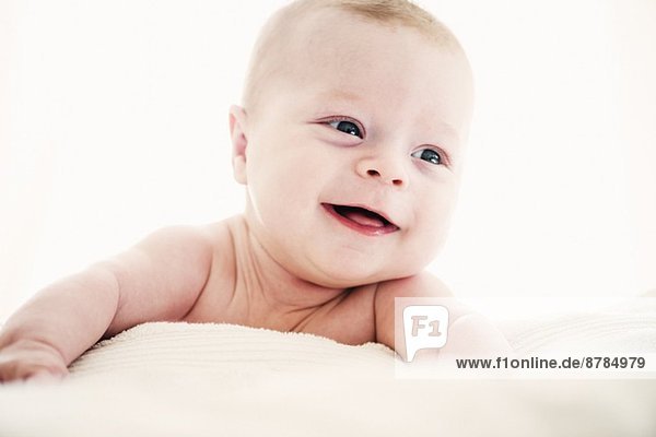 Portrait of smiling baby boy lying on front