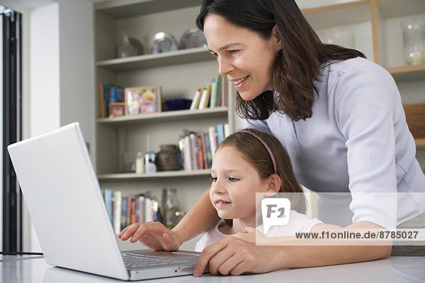 Mother and young daughter using laptop