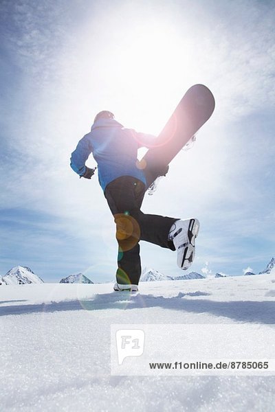 Mature man carrying his snowboard uphill  Obergurgl  Austria