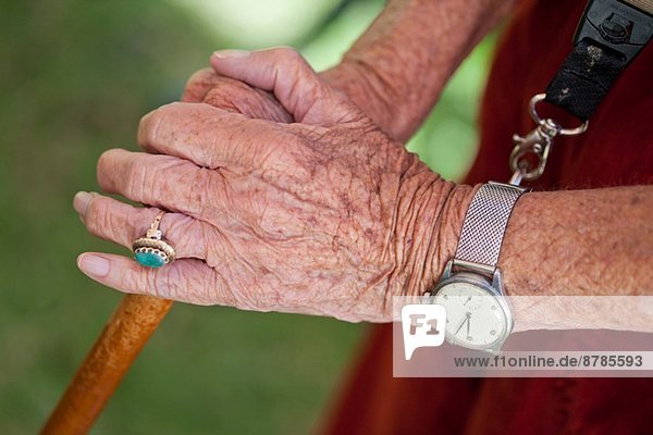 Nahaufnahme der Hände einer älteren Frau mit einem Spazierstock