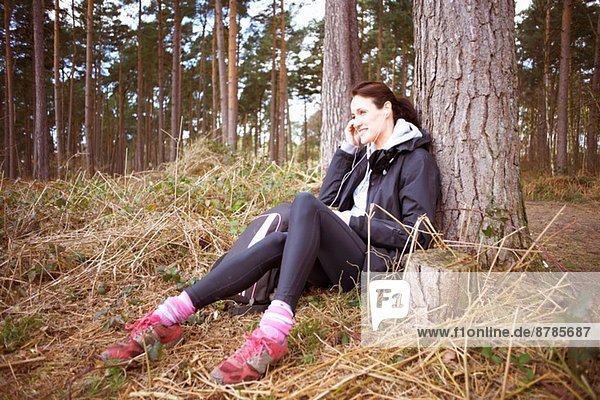 Reife Läuferin beim Telefonieren im Wald