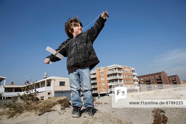 Junge an der Küste  der sich darauf vorbereitet  ein Spielzeugflugzeug zu fliegen  Long Beach  New York State  USA