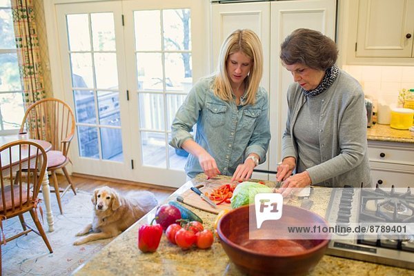 Seniorin und Enkelin hacken Gemüse für Salatschüssel