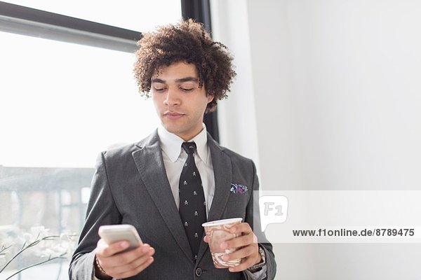 Young man using cell phone with coffee