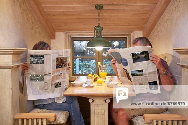 Paare am Frühstückstisch  ignorieren sich gegenseitig  lesen Zeitungen