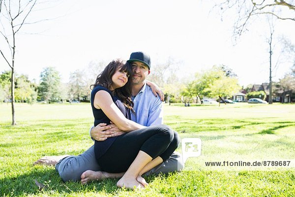 Portrait of mid adult couple sitting in park