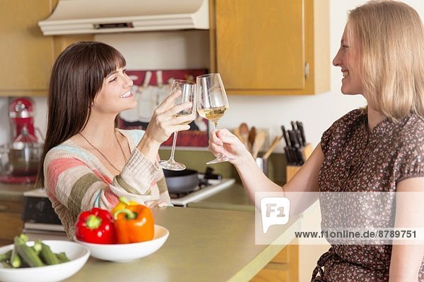 Mittlere erwachsene weibliche Freunde  die in der Küche ein Glas erheben