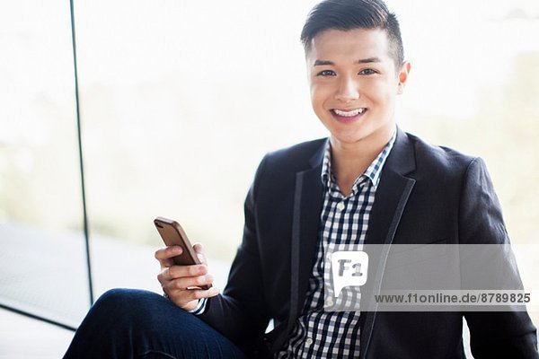 Portrait of young businessman holding smartphone