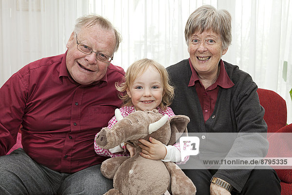Großeltern und die 3-jährige Enkeltochter mit einem Stofftier