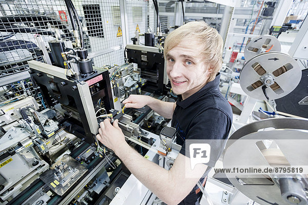 Fabian Kerscher  bundesweit bester Auszubildender  2013 in der Fachrichtung Mechatronik  beim Einstellen der Sensorposition an einer Stanze  Fa. Technical Plastic Systems GmbH  Wackersdorf  Bayern  Deutschland