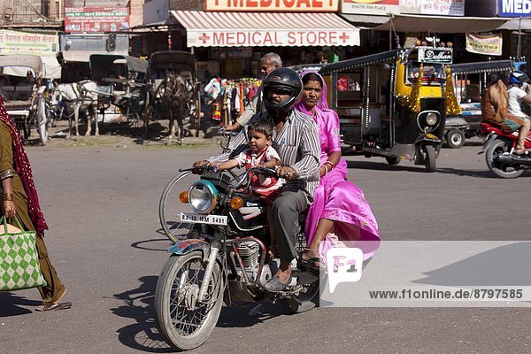 Indian family riding motorcycle  street scene at Sardar Market at Girdikot  Jodhpur  Rajasthan  Northern India