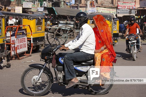 Indian couple riding motorcycle  street scene at Sardar Market at Girdikot  Jodhpur  Rajasthan  Northern India