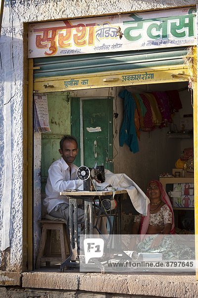 Indian man and wife sewing fabric in village of Rohet in Rajasthan  Northern India
