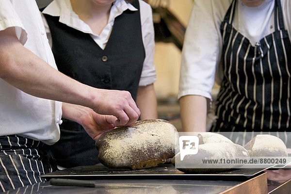 Köche und Kellnerin in der Küche mit frisch gebackenem Brot