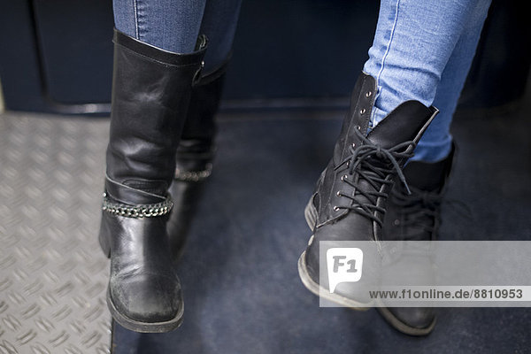 Frauen sitzen zusammen in der U-Bahn  Nahaufnahme der Stiefel