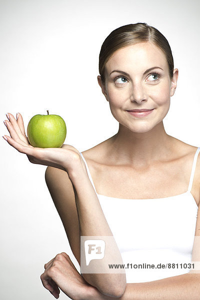 Junge Frau hält grünen Apfel hoch